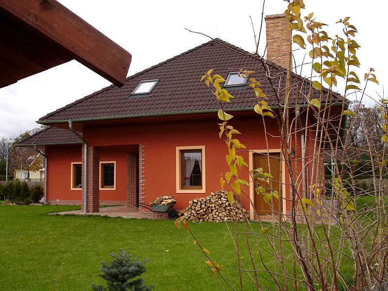 Rodinný dům v terakotové barvě s dřevěnou pergolou a skládaným dřevem